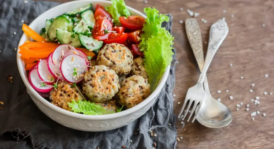 Kolorowa miska pełna zdrowia: kotleciki z komosy ryżowej, rzodkiewka, ogórek, pomidorki, papryka. Idealne przepisy na dietę przeciwzapalną.