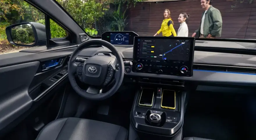 Wnętrze Toyoty bZ4X z ekranem nawigacji. Rodzina na zewnątrz, zastanawia się nad ceną i możliwościami tego elektrycznego SUV-a.