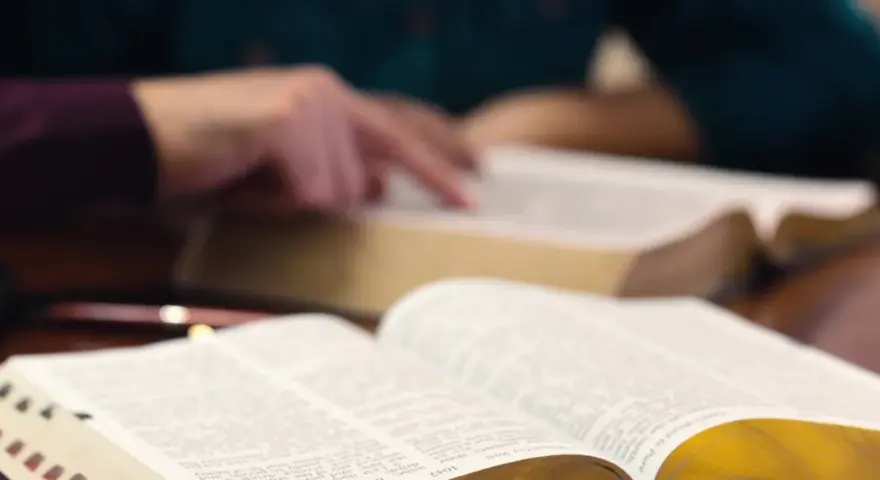 Hände studieren die Bibel, ein Symbol für tiefen Glauben und spirituelle Suche.