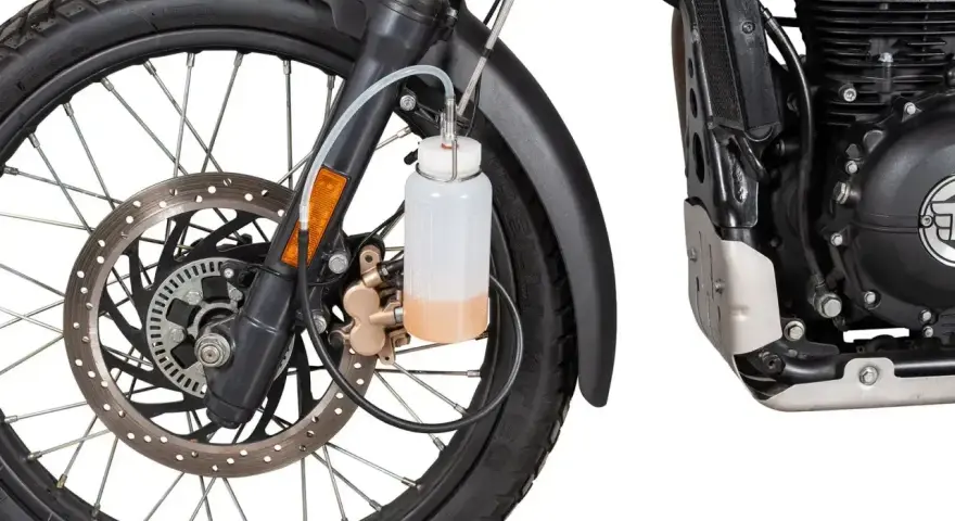 Przygotowanie motocykla do jazdy: odpowietrzanie hamulców z ABS. Widać koło, tarczę hamulcową i zbiorniczek z płynem.