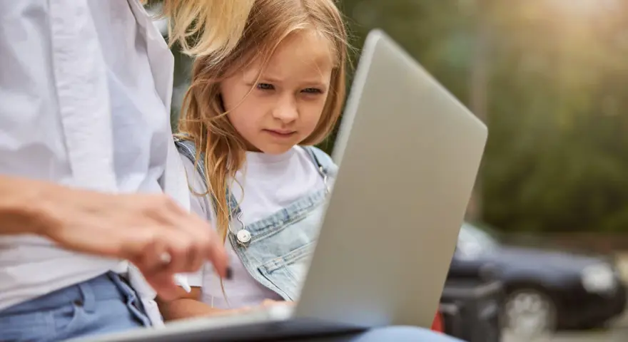 Mama z córką przeglądają internet, szukając informacji, kiedy jest rekrutacja do żłobka.