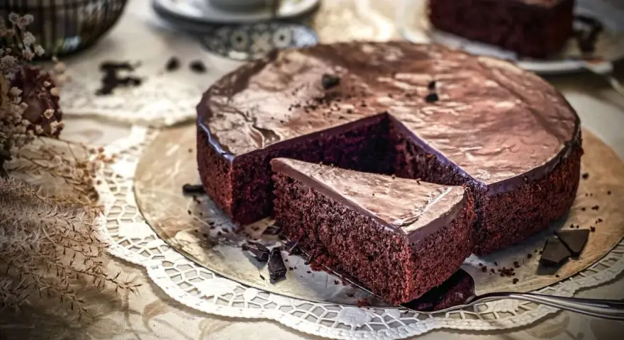 Ein saftiger Schokokuchen mit glänzender Glasur, ein Stück herausgeschnitten. Perfekt für ein Schokokuchen Rezept.