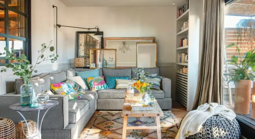 Salones muy pequeños con encanto: sofá gris, cojines coloridos, alfombra étnica, mesa de madera rústica y plantas.