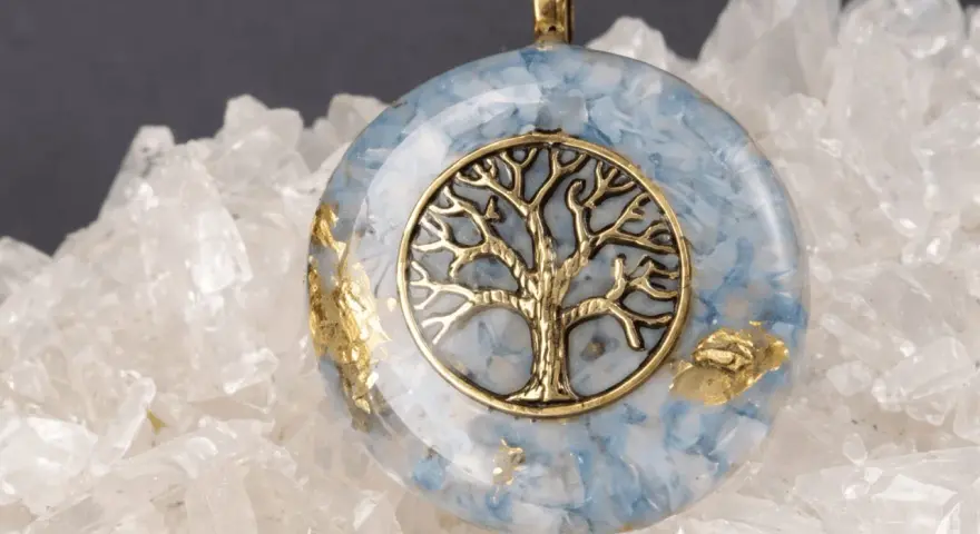 Colgante de orgonita con árbol de la vida dorado sobre fondo de cuarzo. El significado de la orgonita se refleja en su energía protectora.