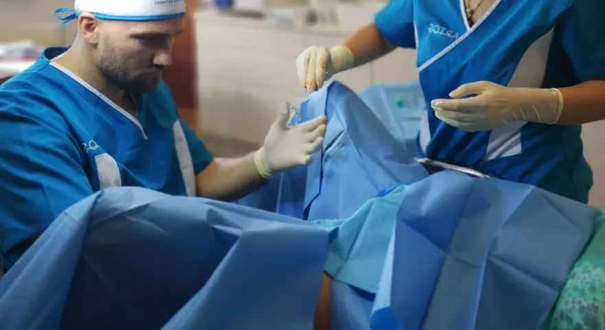 Chirurg i asystentka w rękawiczkach przygotowują się do zabiegu. Zdjęcia nieudana labioplastyka mogą pokazywać takie momenty.