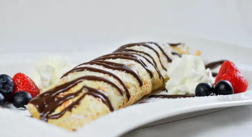Palatschinken mit Eis, Schokosauce und frischen Beeren. Ein süßer Genuss, der auf der Zunge zergeht.