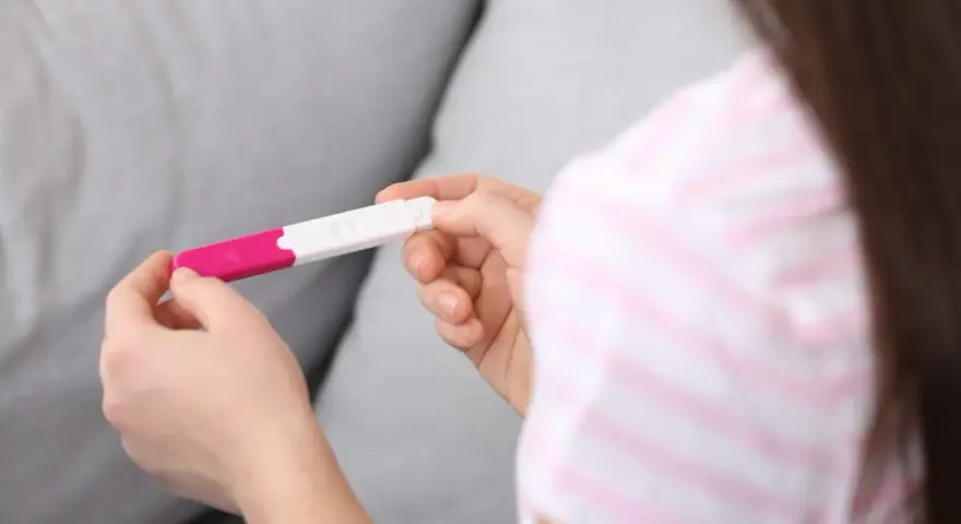 Dłonie trzymające test ciążowy. Wynik wskazuje na 1 miesiąc ciąży, co może być początkiem nowej, pięknej historii.