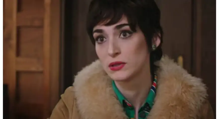 Una donna con un taglio di capelli corto e scuro, trucco marcato e un cappotto di pelliccia chiara. Le anticipazioni di Cuori 3 promettono colpi di scena.