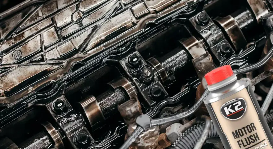 Silnik Peugeot 307 1.6 benzyna po płukaniu. Widać wałki rozrządu i elementy pokryte olejem. Obok butelka płukanki K2 Motor Flush.