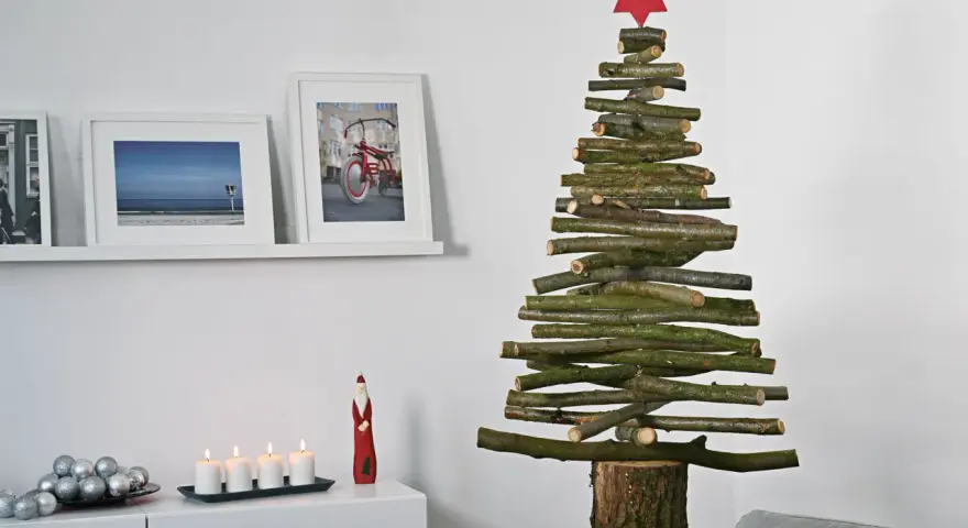 Ein rustikaler Tannenbaum aus Holzlatten, selbstgemacht, mit rotem Stern. Daneben Bilder und Kerzen.