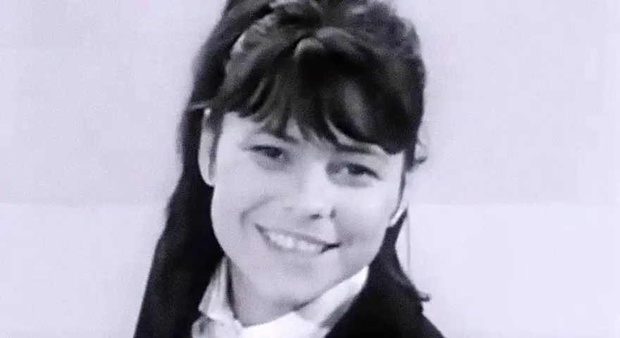 Uśmiechnięta Karin Stanek, jak malowana lala, w czarnym żakiecie i białej koszuli.