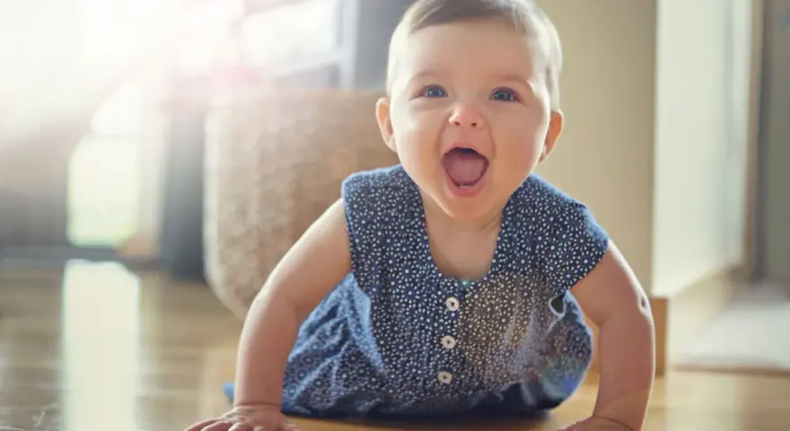 Ein fröhliches Baby hebt Arme und Beine in Bauchlage, bereit zum Krabbeln.