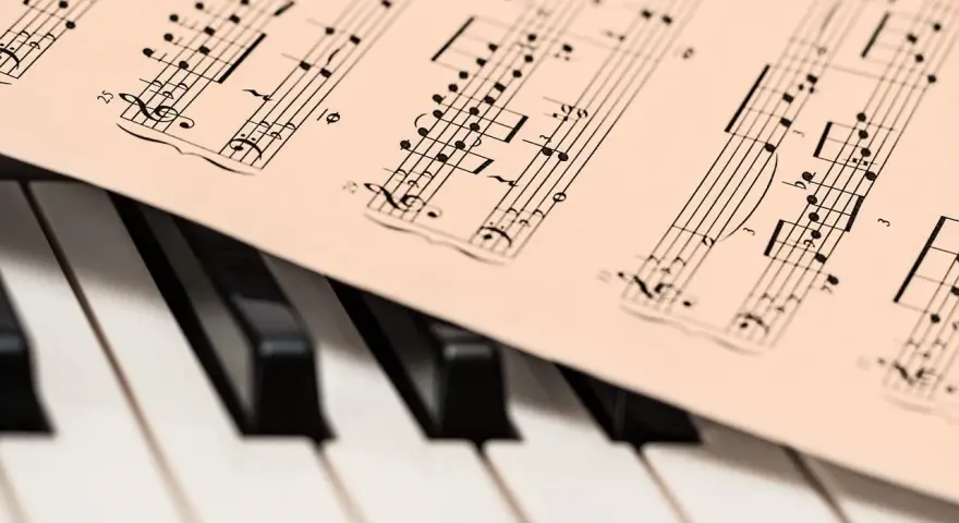 Partytura z nutami na klawiaturze pianina, gotowa do zagrania najsłynniejsze utwory jazzowe.