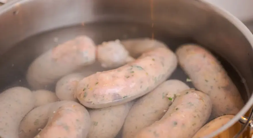 Biała kiełbasa gotuje się w garnku. Poznaj prosty sposób, jak parzyć białą kiełbasę, by była idealna.