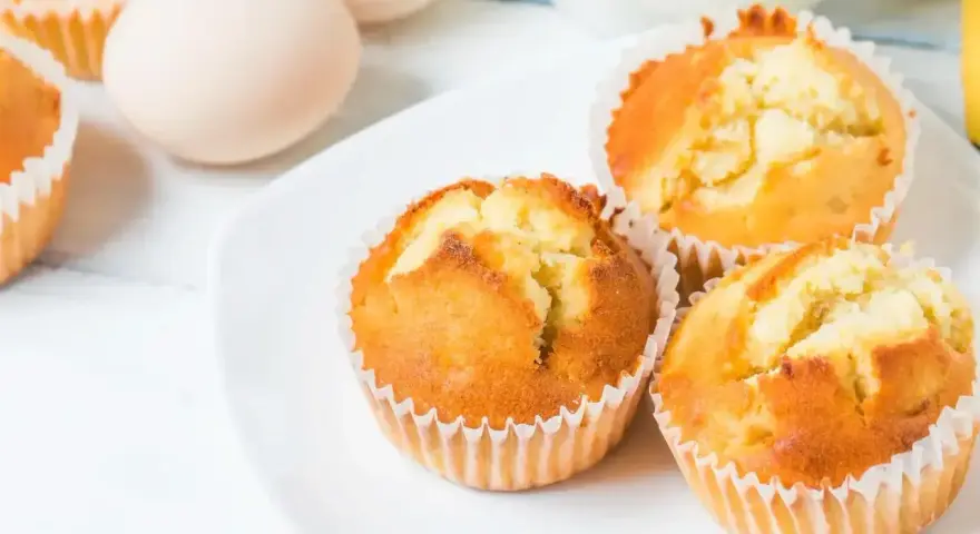 Puszyste babeczki z airfryer na białym talerzu, obok jajka. Idealne na szybkie śniadanie.