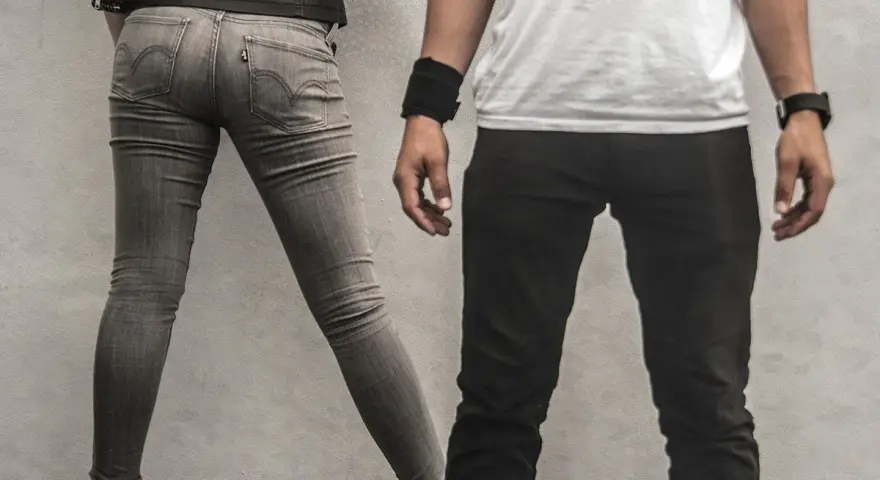 Szara, dopasowana para jeansów, widać metkę Levi's. Czy to rozmiar w25? Obok mężczyzna w czarnych spodniach.