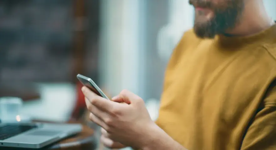 Uomo con barba usa smartphone, forse per capire cosa sono i gb del cellulare e quanto spazio ha per foto e app.