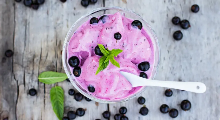Ein Schälchen mit cremigem Johannisbeer Eis, garniert mit frischer Minze und ganzen Beeren.