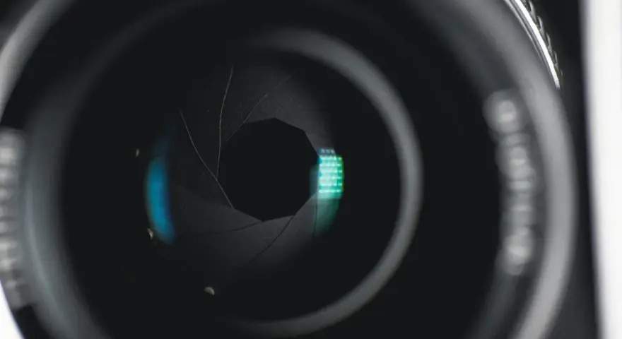 Ouverture d'objectif de caméra, diaphragme réglé sur f 2.8, révélant des reflets bleus et verts.