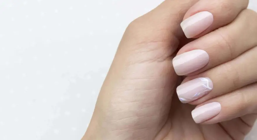 Main gauche avec des ongles pastel, dont un orné d'un motif floral délicat. Parfait pour faire les ongles.