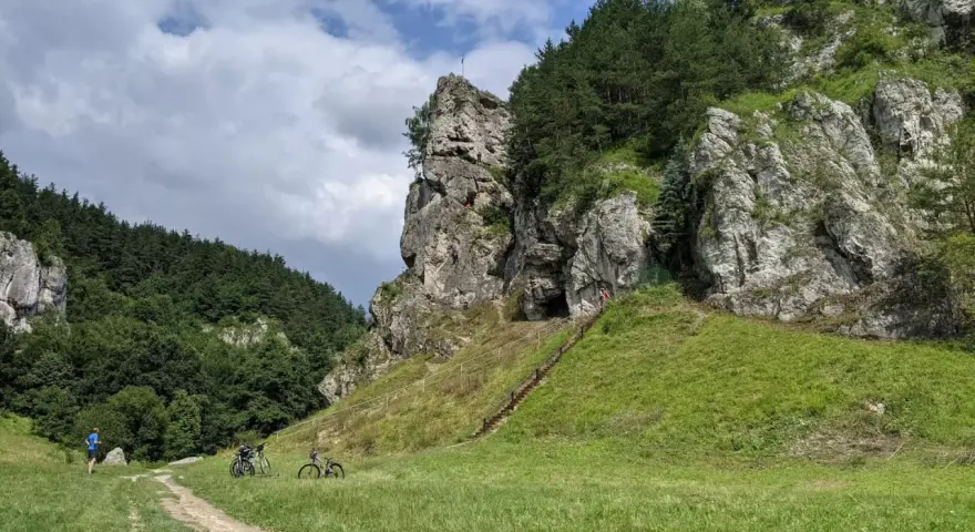 Dolina Kobylańska zachwyca skalnymi formacjami i zielonymi zboczami. Na ścieżce rowerzyści, a na skałach wspinacze.