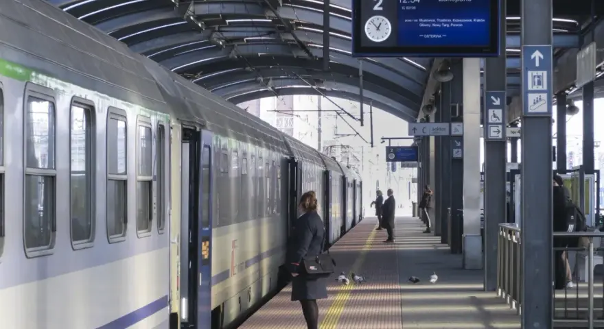 Pociąg na peronie, tablica informacyjna z trasą do Zakopanego, pasażerowie.