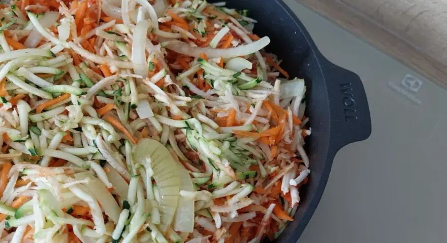 Start przygotowania keto ryby po grecku: starta marchewka, cukinia i cebula w naczyniu.