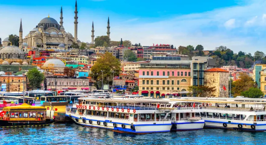 A vibrant cityscape of Istanbul, with the Suleymaniye Mosque dominating the skyline. Ferries and buses line the waterfront, ready for a 3-day Istanbul adventure.