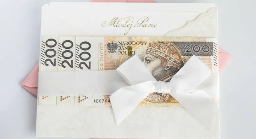 Elegancka koperta z banknotami 200 zł, przewiązana białą wstążką. Idealny prezent ślubny, choć warto pamiętać o potencjalnym podatku od prezentów ślubnych.