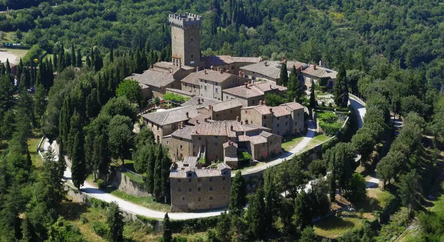 Il castello di Gargonza, un borgo medievale in pietra con torre, immerso nel verde della Toscana.
