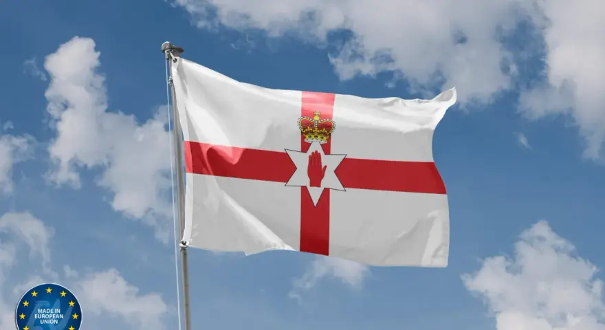 Flaga Irlandii Północnej powiewa na tle błękitnego nieba z chmurami. Symbolizuje historię i tożsamość regionu.