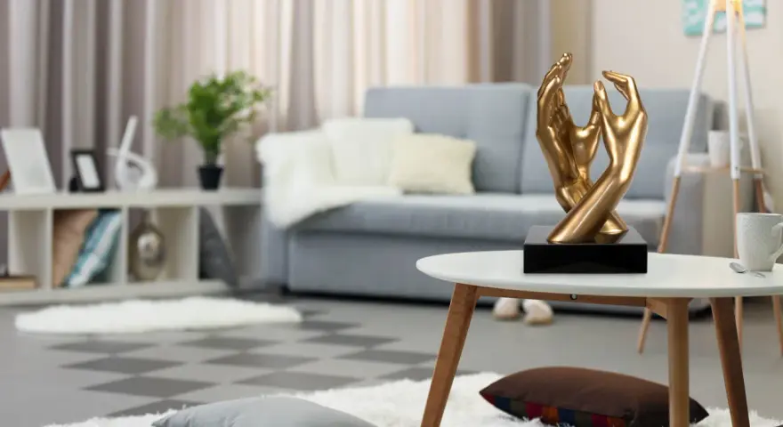 Esculturas de manos doradas, arte moderno que adorna un salón acogedor con sofá gris y alfombras mullidas.