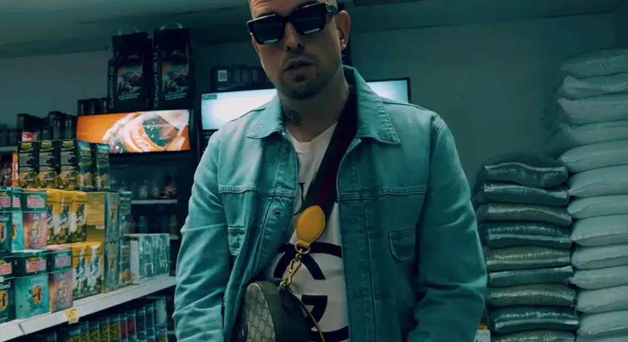 Sentino Malik w dżinsowej kurtce i okularach stoi w sklepie, otoczony towarem.