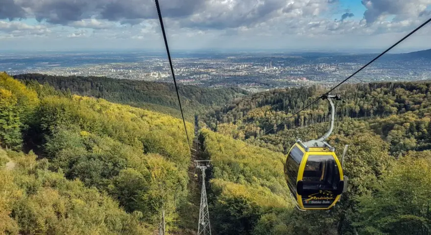 Kolejka linowa wjeżdża na szlak na Klimczok z Bielska, oferując widok na miasto i jesienne lasy.