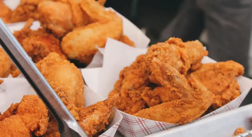 Un surtido de crujiente pollo frito en recipientes de cartón. Las piezas doradas y sabrosas invitan a disfrutar de este clásico.