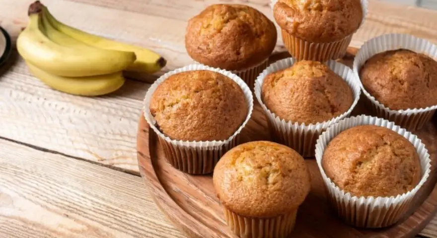 Puszyste babeczki z airfryer, pachnące bananami, ułożone na drewnianej desce.