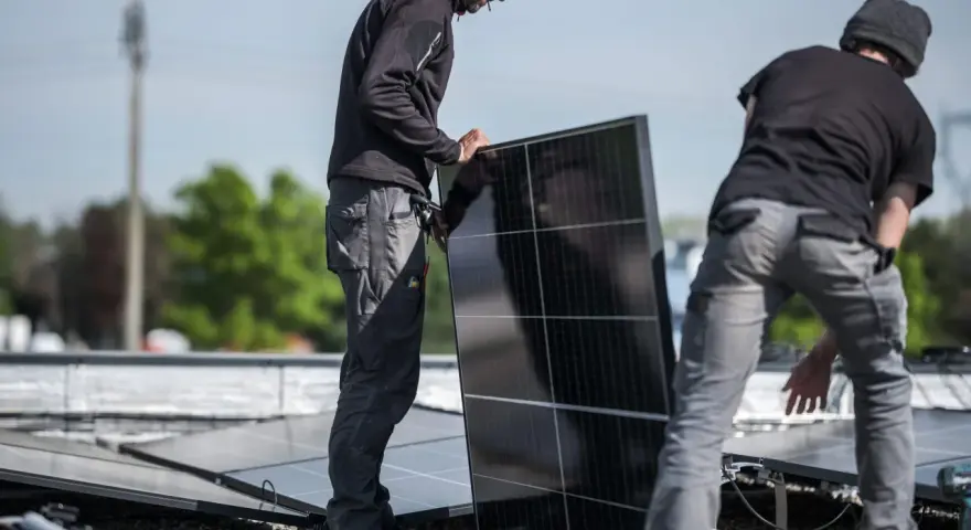 Pracownicy montują panele fotowoltaiczne, przygotowując zgłoszenie rozbudowy instalacji fotowoltaicznej PGE.