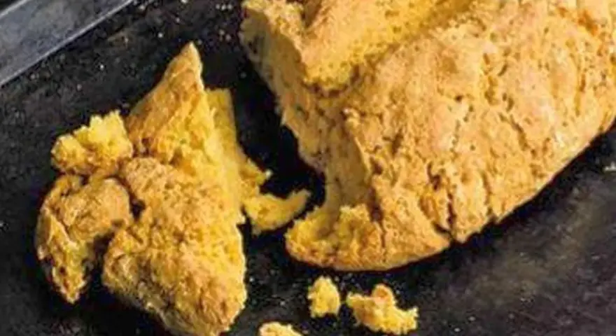 Goldgelbes, rustikales Brot, das nach Rezepten mit Lupinen aussieht, liegt auf einem dunklen Blech.