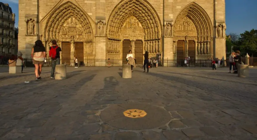 Devant Notre-Dame, le point zéro altitude marque le centre de Paris. Des visiteurs admirent la façade.