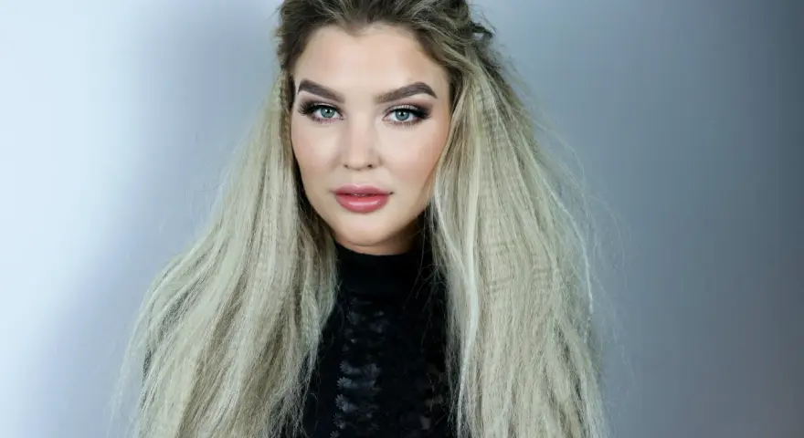 En kvinna med blå ögon och en snygg makeup har sitt blonda hår stylat med en våffla.