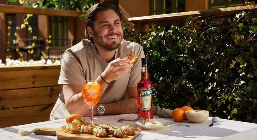 Man njuter av en Aperol Spritz och tilltugg på en solig uteservering.