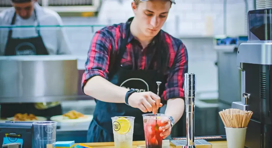 Ein junger Mann, der als Werkstudent 20 Stunden pro Woche arbeitet, mixt Getränke in einem Streetfood-Laden.