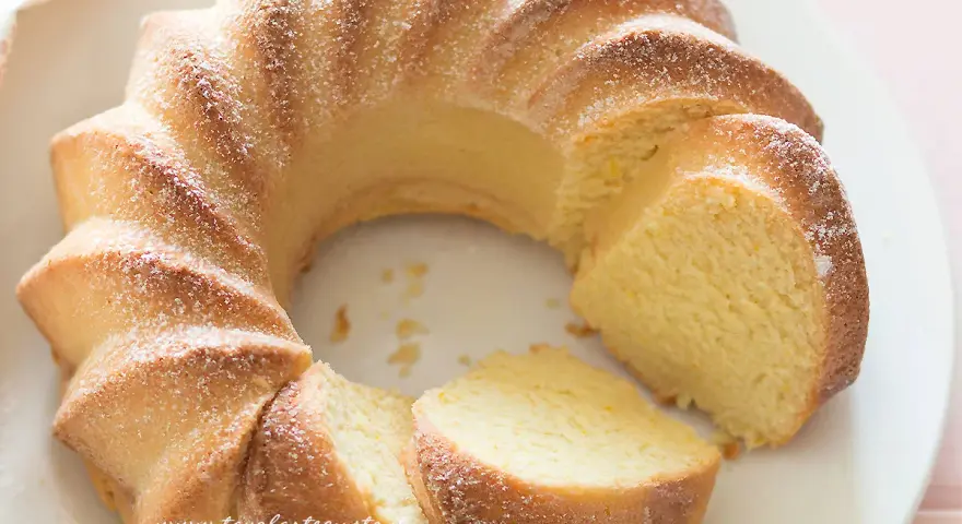 Una soffice torta di ricotta, spolverata di zucchero a velo, con una fetta tagliata.