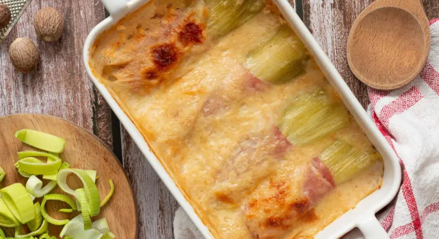 Gratin de poireaux au jambon, doré et crémeux, prêt à être dégusté. Une recette réconfortante.