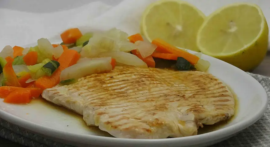 Fettine di tacchino appetitose, cotte alla griglia, servite con verdure miste e spicchi di limone.