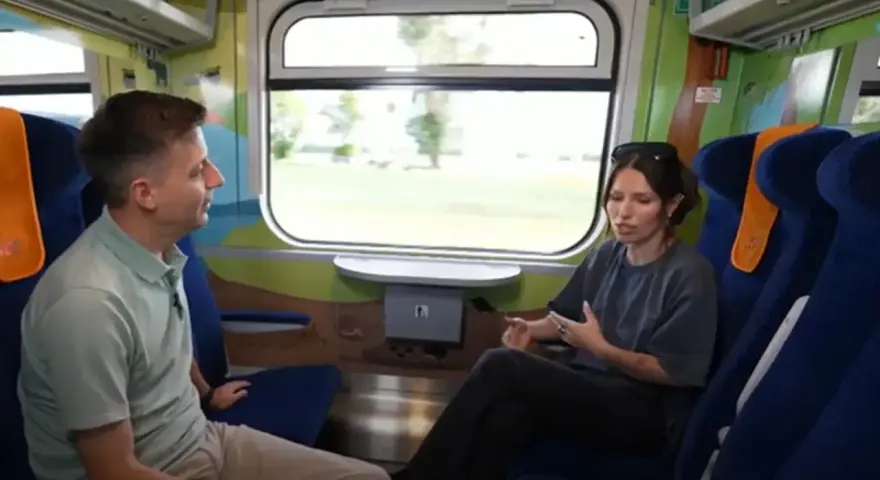Rozmowa w wagonie z kolorowymi grafikami, być może w ramach specjalnego **metro programu** dla dzieci.