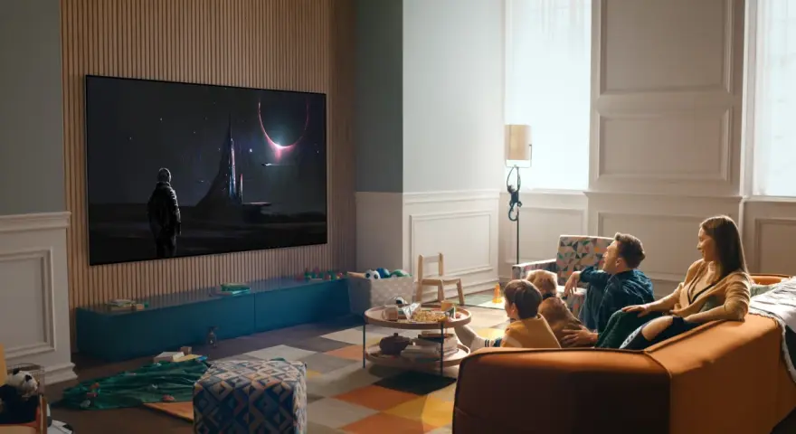 Familj tittar på en rymdfilm på TV:n, kanske via iptv tele2. En astronaut står framför en futuristisk stad under en solförmörkelse.