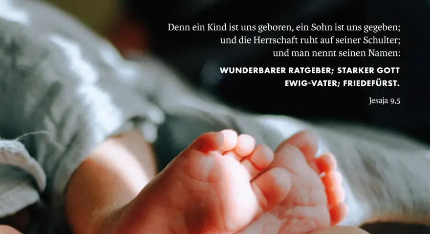 Zarte Füße eines Neugeborenen, umgeben von weichen Stoffen. Der Text zitiert Jesaja 9,5: "Wunderbarer Ratgeber, starker Gott, Ewig-Vater, Friedefürst.