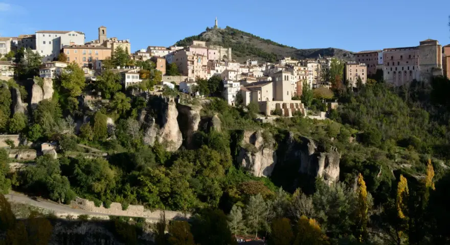 La ruta San Julián el Tranquilo en Cuenca: casas colgadas sobre riscos, vegetación frondosa y un cielo azul.