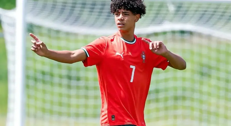 Cristiano Ronaldo Jr. con pelo rizado y camiseta roja con el número 7, señalando con el dedo índice.